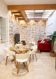 Salón comedor de Casa Señorial Rivadavia con mesa para cuatro personas, techo de madera y pared de piedra original