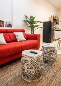 Salón con sofá rojo y cocina abierta totalmente equipada en Casa Señorial Rivadavia, Cádiz