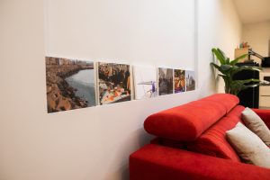 Detalle decorativo del salón de Casa Señorial Rivadavia con fotografías de Cádiz y sofá rojo