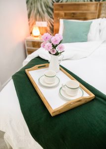 Detalle de la cama de matrimonio de Casa Señorial Rivadavia con bandeja de desayuno y flores decorativas