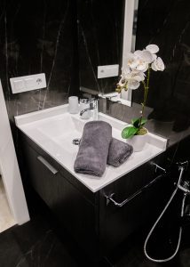Lavabo con espejo, orquídea decorativa y toallas en el baño de Casa Señorial Rivadavia