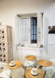 Comedor de Casa Señorial Rivadavia con mesa de cristal y ventana interior que aporta luz natural al apartamento
