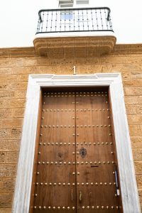 Entrada principal de Casa Señorial Rivadavia con puerta histórica de madera y balcón tradicional en Cádiz