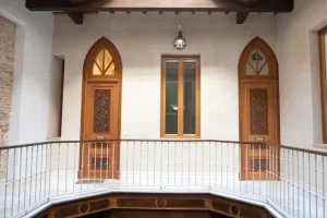 Galería interior con puertas de madera, barandilla y detalles históricos en Palacio Conde Casa-Brunet