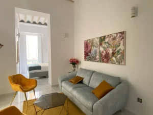 Salón de Casa Señorial Rivadavia con sofá, decoración moderna y vista al dormitorio en el centro histórico de Cádiz
