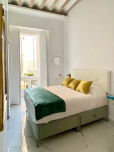 Dormitorio de Casa Señorial Rivadavia con cama de matrimonio, balcón y vistas a la Plaza de San Antonio en Cádiz