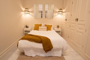 Dormitorio con cama doble, iluminación cálida y mobiliario de estilo contemporáneo.