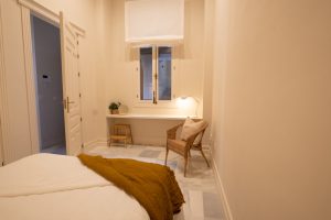 Habitación con cama de matrimonio, escritorio junto a la ventana y luz natural.