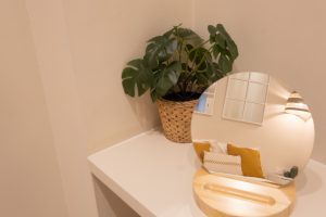 Detalle de la decoración del dormitorio con espejo, planta y acabados cuidados.