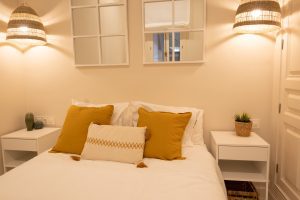 Cabecero, cama de matrimonio y mesillas con iluminación ambiental en el dormitorio.