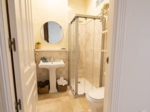 Baño completo con ducha de cristal, lavabo y acabados modernos en Casa Apolo.