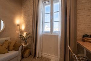 Detalle del salón con sofá, ventana, iluminación ambiental y zona de comedor en Casa Apolo.