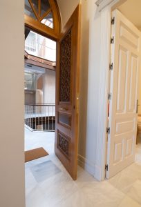 Entrada del apartamento Casa Apolo con puerta de madera restaurada y vistas al patio interior del edificio.