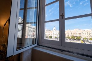 Ventana abierta del apartamento con vistas a la Plaza de San Juan de Dios y al centro histórico de Cádiz.