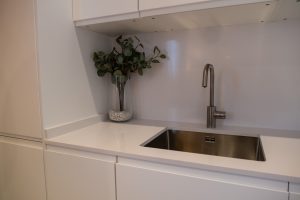 Detalle de la cocina equipada con fregadero, mobiliario blanco y encimera moderna en Casa Apolo.