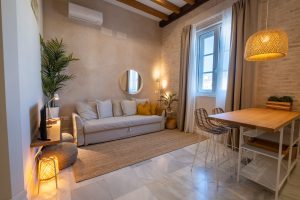 Salón luminoso con sofá, comedor, cocina abierta y decoración cálida en Casa Apolo.