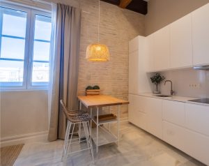 Cocina totalmente equipada y zona de comedor junto a una ventana con vistas al centro de Cádiz.
