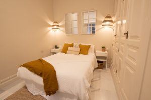 Dormitorio principal con cama de matrimonio, mesillas y decoración luminosa en Casa Apolo.