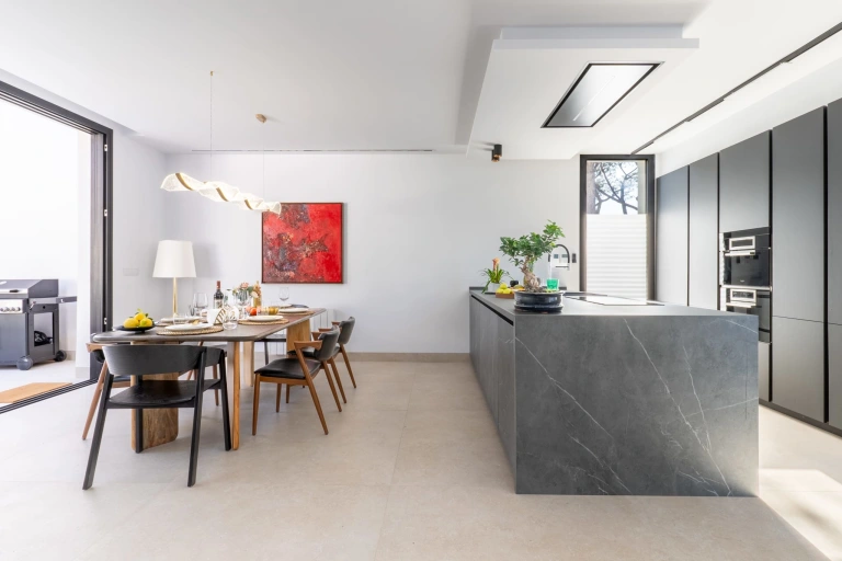 Cocina abierta con isla central y comedor moderno en una villa exclusiva de InnCádiz.